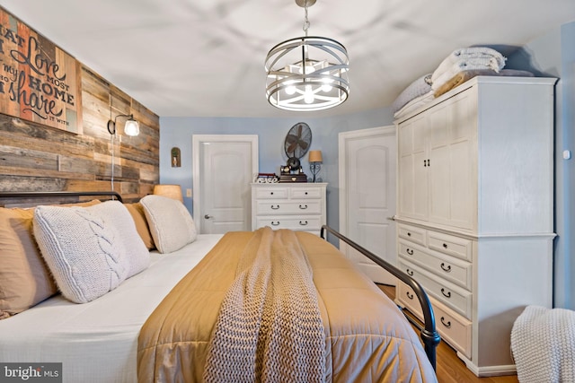 bedroom with wooden walls, a closet, a chandelier, and hardwood / wood-style flooring