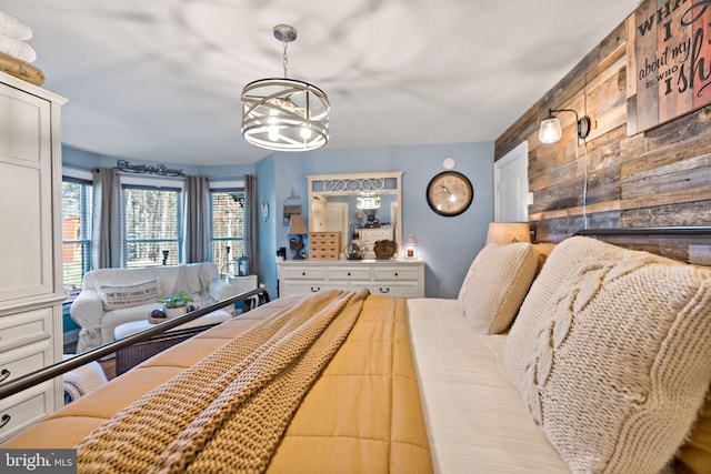 bedroom featuring wood walls and an inviting chandelier