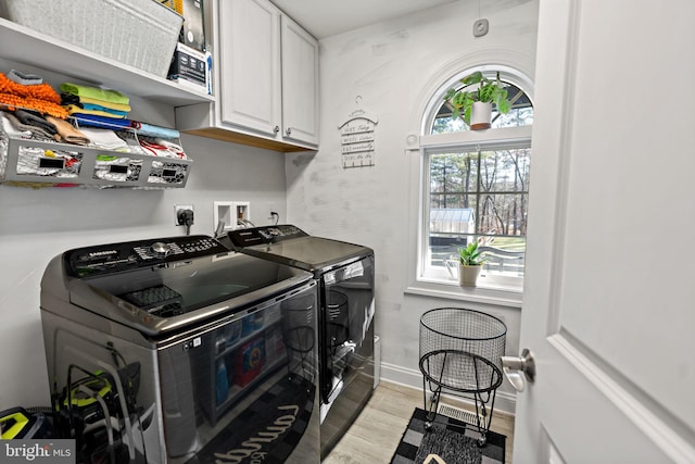 washroom featuring cabinets, light wood-type flooring, and washing machine and clothes dryer