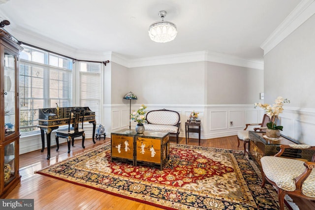 sitting room featuring wainscoting, crown molding, and hardwood / wood-style floors