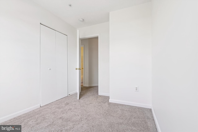 unfurnished bedroom featuring a closet and light carpet