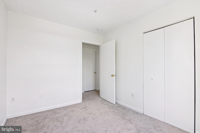 unfurnished bedroom with light colored carpet and a closet