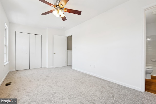 unfurnished bedroom with ceiling fan, ensuite bathroom, a closet, and carpet floors