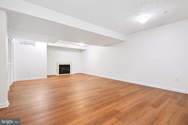 unfurnished living room with a textured ceiling and light hardwood / wood-style floors