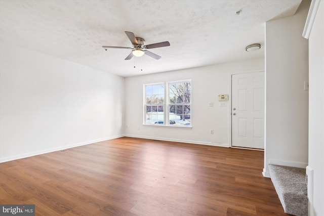 interior space with a textured ceiling, ceiling fan, and dark hardwood / wood-style flooring