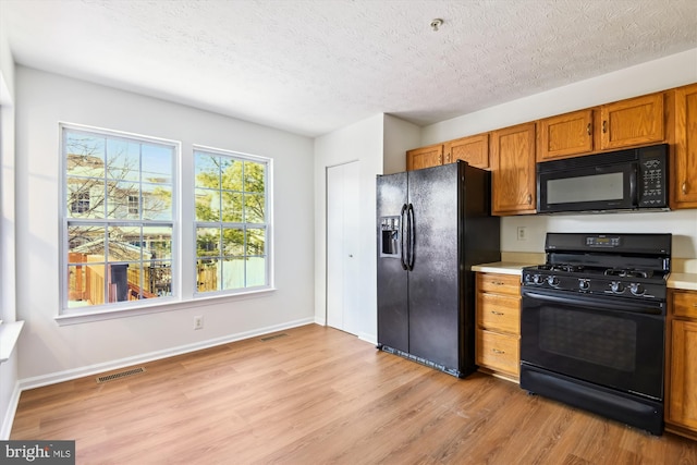 kitchen with black appliances, light hardwood / wood-style floors, and a textured ceiling