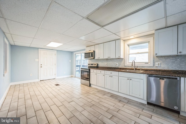 kitchen with white cabinetry, sink, tasteful backsplash, a paneled ceiling, and appliances with stainless steel finishes