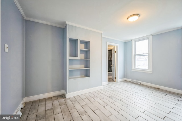 empty room with built in shelves, light wood-type flooring, and ornamental molding