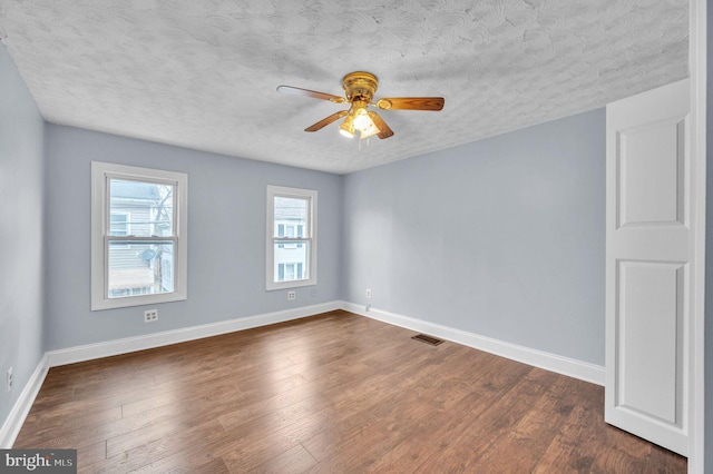 empty room featuring ceiling fan, dark wood-type flooring, and a textured ceiling