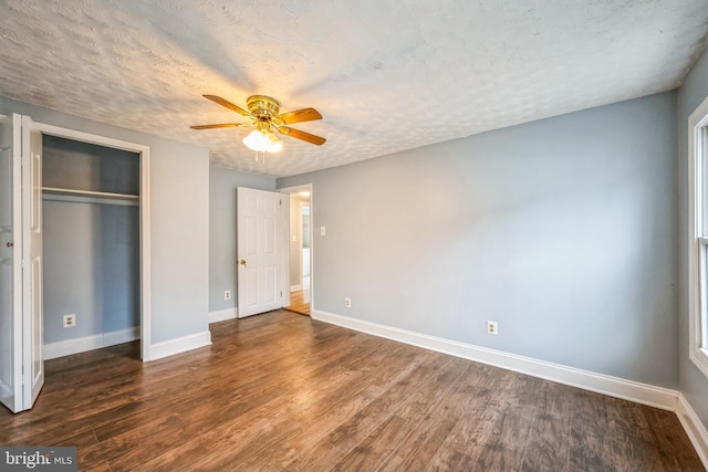 unfurnished bedroom featuring a closet, a textured ceiling, dark hardwood / wood-style floors, and ceiling fan