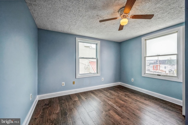 empty room featuring ceiling fan, a textured ceiling, and dark wood-type flooring