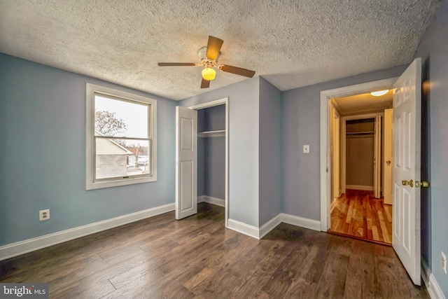 unfurnished bedroom with a textured ceiling, a closet, ceiling fan, and dark wood-type flooring