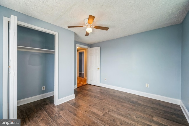 unfurnished bedroom with a textured ceiling, dark hardwood / wood-style flooring, a closet, and ceiling fan