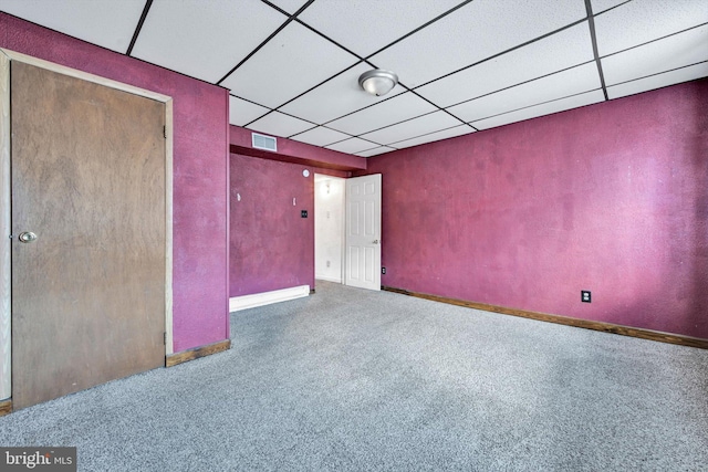 empty room featuring a paneled ceiling and carpet floors