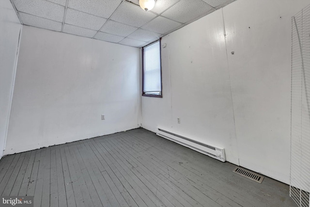 empty room featuring a paneled ceiling, dark wood-type flooring, and a baseboard radiator