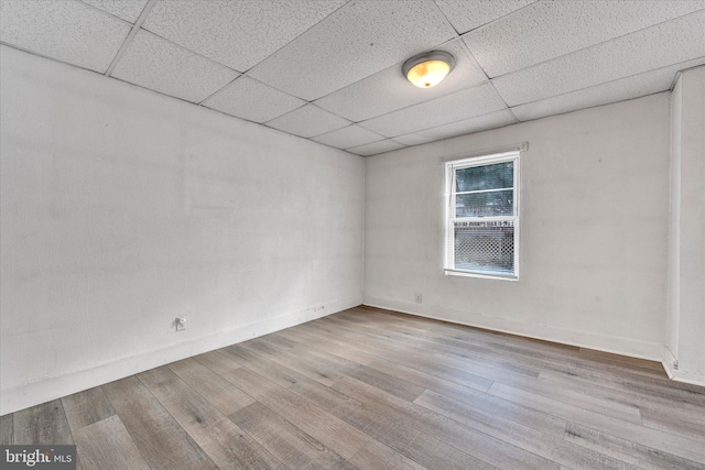 spare room with a paneled ceiling and light hardwood / wood-style floors