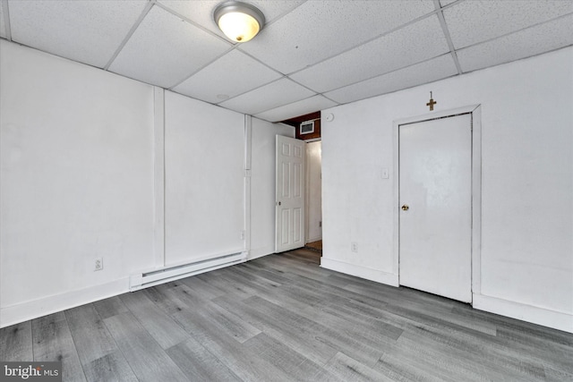 basement with a paneled ceiling, hardwood / wood-style floors, and a baseboard heating unit