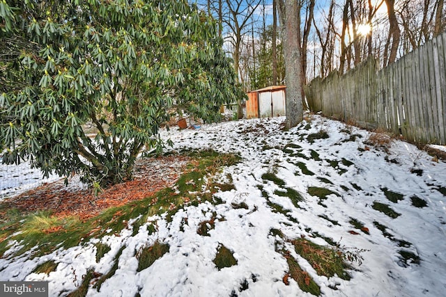 snowy yard featuring a storage shed