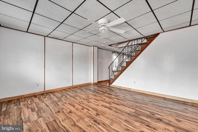 basement featuring wood-type flooring, a paneled ceiling, and ceiling fan