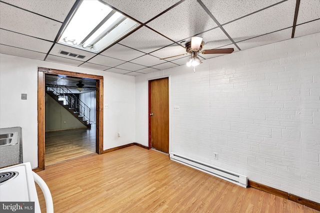 basement with hardwood / wood-style floors, a paneled ceiling, ceiling fan, and a baseboard heating unit