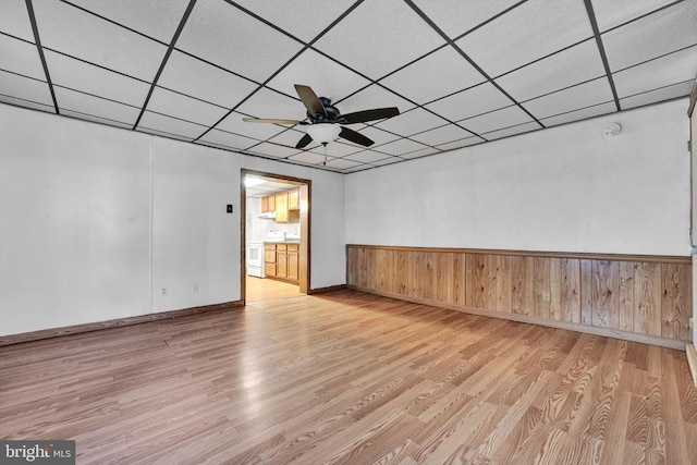 spare room featuring a paneled ceiling, wooden walls, ceiling fan, and light hardwood / wood-style floors