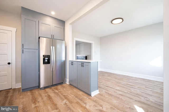 kitchen with gray cabinetry, stainless steel fridge, kitchen peninsula, and light hardwood / wood-style flooring