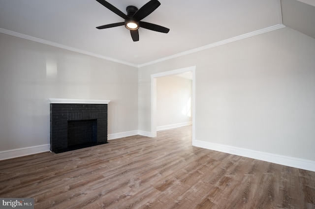 unfurnished living room with wood-type flooring, a brick fireplace, and crown molding