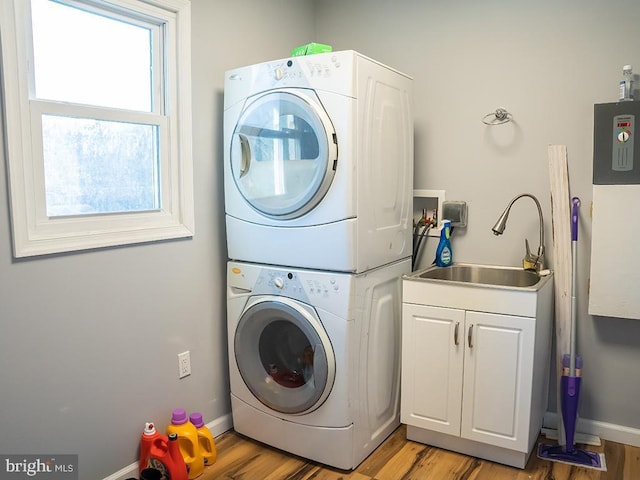 laundry area with cabinets, light hardwood / wood-style floors, stacked washer and clothes dryer, and sink