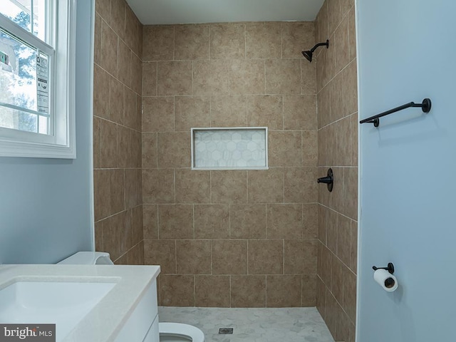 bathroom featuring tiled shower, vanity, and toilet