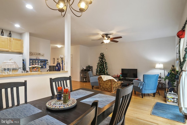 dining area with ceiling fan with notable chandelier and light wood-type flooring