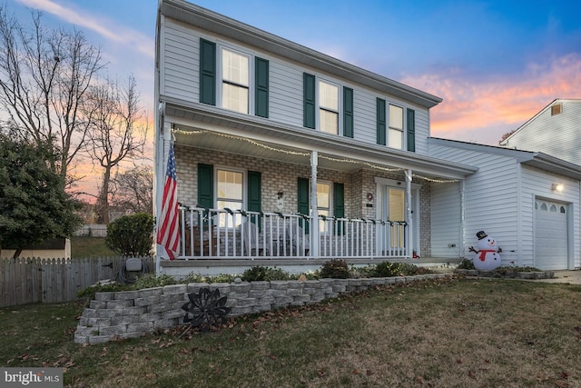 view of front of home featuring a lawn, a porch, and a garage