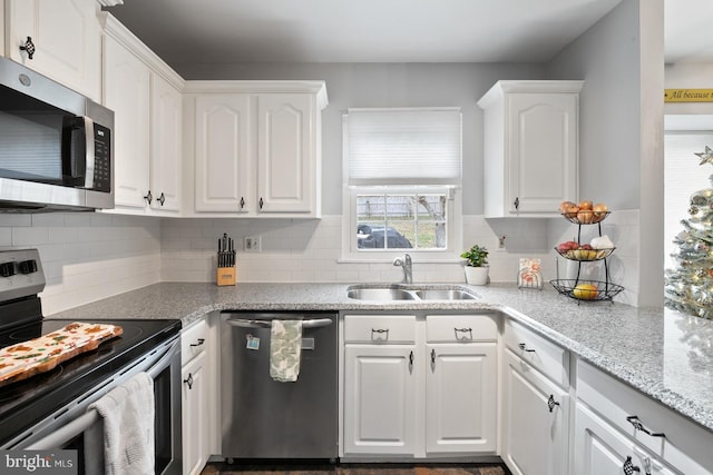 kitchen with decorative backsplash, sink, white cabinets, and stainless steel appliances