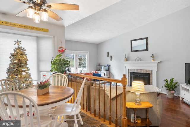 dining space featuring a textured ceiling, ceiling fan, a fireplace, and dark wood-type flooring