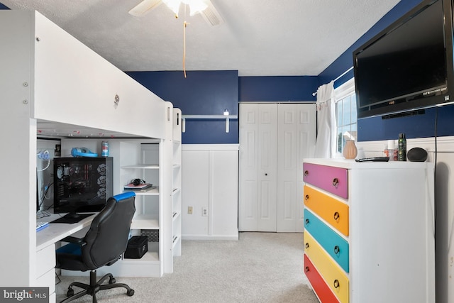 carpeted home office with a textured ceiling and ceiling fan