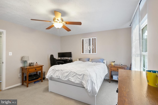 bedroom with a textured ceiling, light colored carpet, and ceiling fan