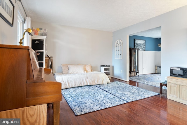 bedroom with a textured ceiling and dark hardwood / wood-style flooring