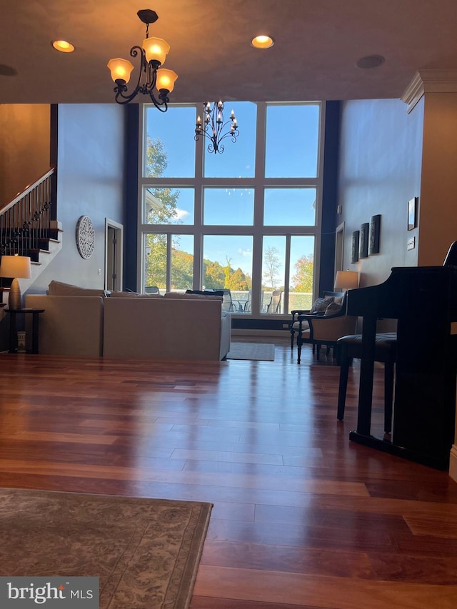 living area featuring a chandelier, recessed lighting, dark wood-type flooring, a high ceiling, and stairs