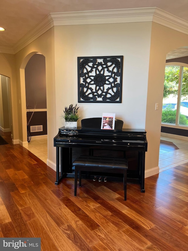 room details featuring baseboards, visible vents, arched walkways, ornamental molding, and wood finished floors