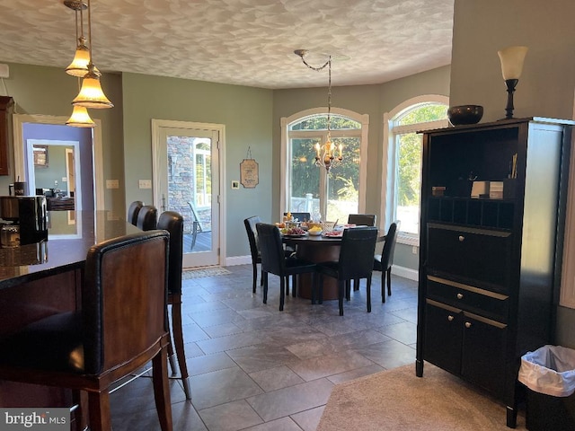 dining space with a chandelier, plenty of natural light, a textured ceiling, and baseboards