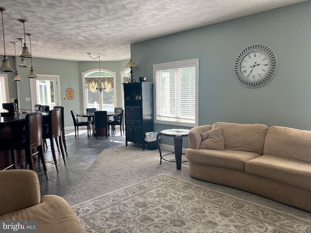 living room with an inviting chandelier, baseboards, and a textured ceiling