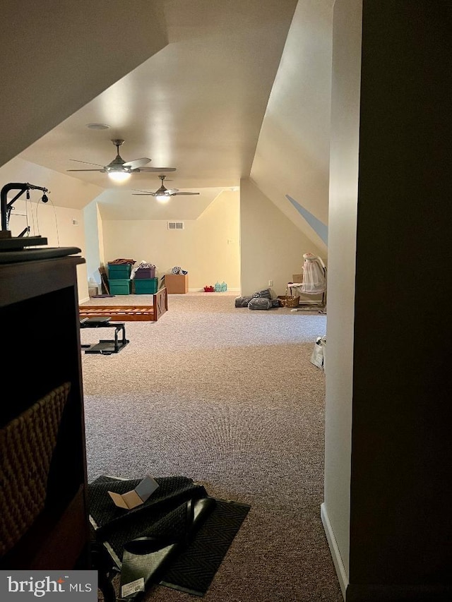 interior space with a ceiling fan, carpet flooring, vaulted ceiling, and visible vents