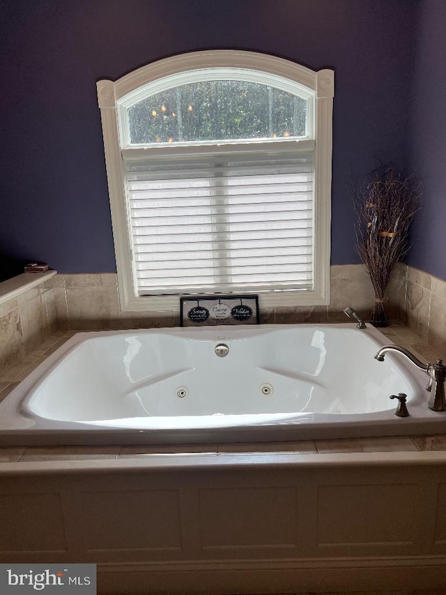 bathroom featuring a jetted tub and a wealth of natural light