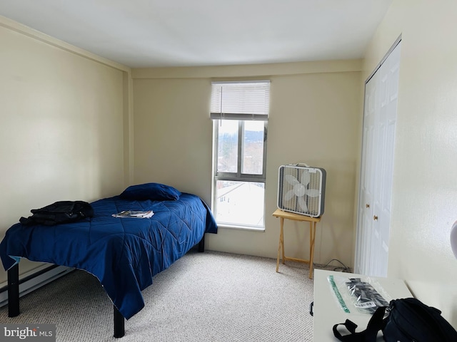 carpeted bedroom featuring a baseboard heating unit and a closet