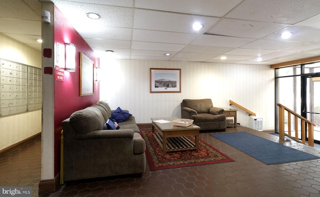 tiled living room with a drop ceiling and a mail area