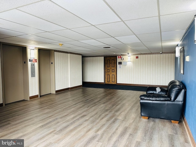 interior space with a drop ceiling and hardwood / wood-style flooring