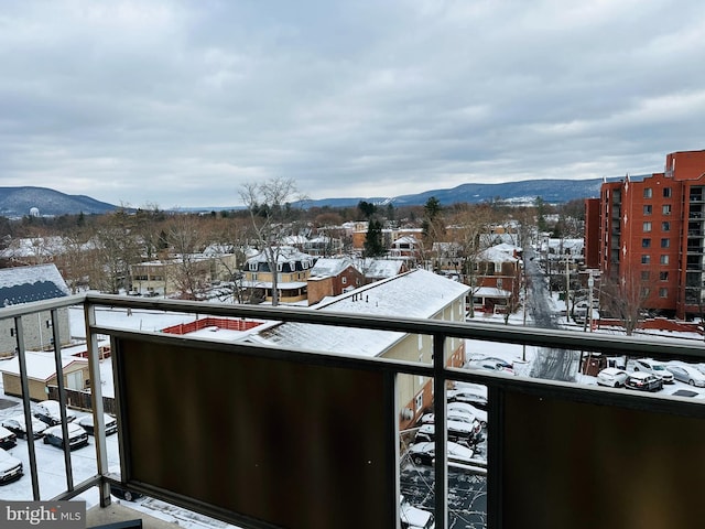 snow covered back of property featuring a mountain view