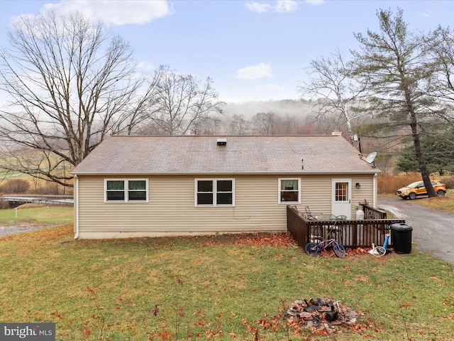 rear view of house with a wooden deck and a yard