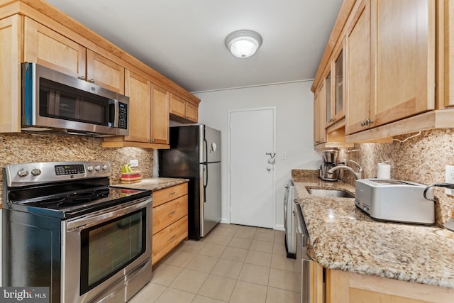 kitchen with light stone counters, sink, stainless steel appliances, and tasteful backsplash