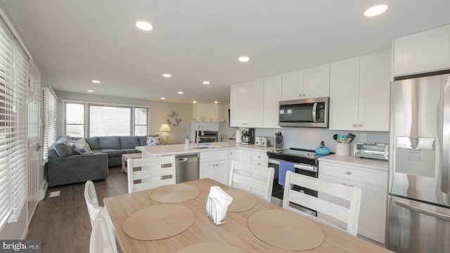 kitchen featuring white cabinets, sink, dark hardwood / wood-style floors, appliances with stainless steel finishes, and kitchen peninsula