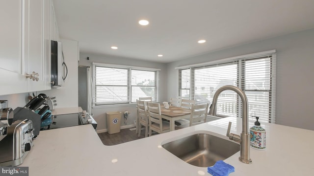 kitchen with black range, dark hardwood / wood-style floors, white cabinetry, and sink